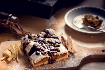 Freshly baked apple pie sprinkled with powdered sugar and topped with chocolate. Delicious homemade pastries with shallow depth of field.
