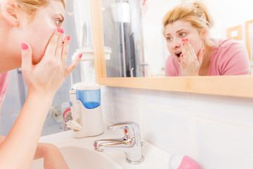 Scared woman washing her face under sink