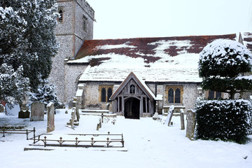 Ringmer church, East Sussex, uk the church and the wooden entrance to the church snow is on the ground on the roof and on the trees in the church yard