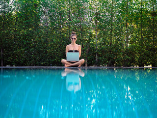 smiling digital Nomad Bikini Girl working with her laptop outdoor at the pool 