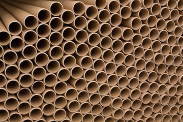 A bunch of brown industrial paper core. A lot of paper cores or paper tubes. Brown paper rolls.