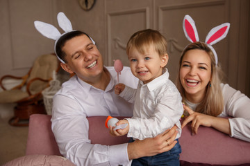 Happy Easter. Young joyful family with child celebrating Easter day. Mother and father wearing...