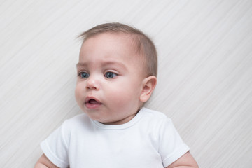 Blue-eyed baby boy on white wooden background