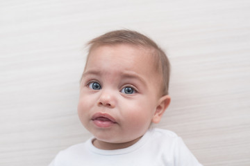 Blue-eyed baby boy on white wooden background