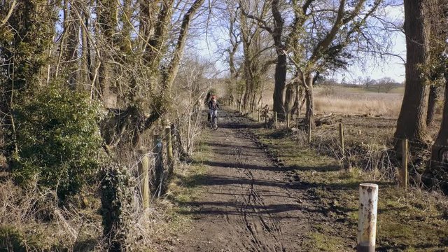Girl slowly rides through muddy dirt track. Baker Path, Tarvin, Cheshire, England