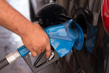 Hand holding pumping gasoline fuel in car at gas station