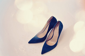 Elegant and stylish blue leather or suede wedding bridal shoes decorated by crystal close up shot. Colorful background.