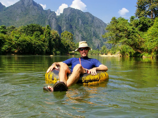 Tourist going down Nam Song River in a tube surrounded by karst scenery in Vang Vieng, Vientiane Province, Laos.