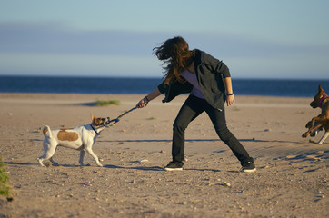Woman playing with her dogs on a beach