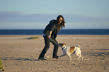 Woman playing with her dogs on a beach