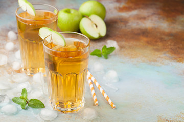 Two glasses of green Apple juice with mint and ice on an old rusty table. Soft drink on a blue background. With copy space