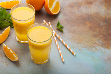 Two glasses with freshly squeezed orange juice and mint on an old rusty blue background. Top view with copy space