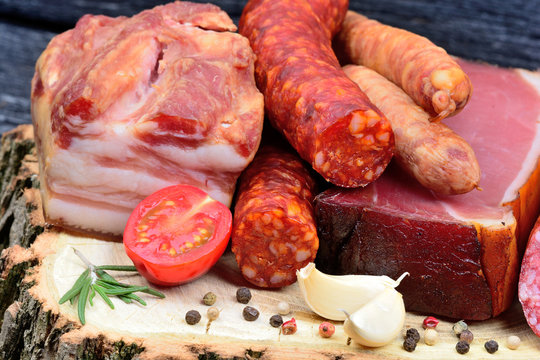 Delicious smoked sausages on a wooden board with spices