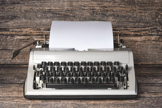 Old typewriter with a piece of paper on a wooden background