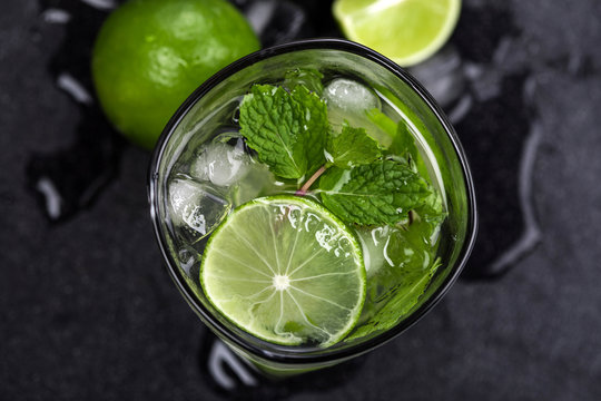 Close up top view or overhead shot of  the fresh mojito cocktail with fresh lime and mint leaf on black stone background