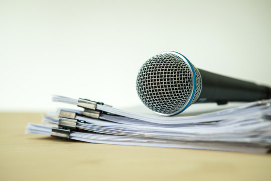 Close up a Microphone with paper document , concept of speaker or teacher preparation to speak in seminar class room