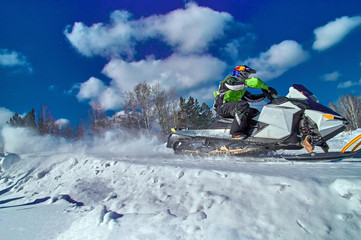 Sports snowmobile is riding at high speed. Extreme competitions on a sunny winter day. Concept quick movement. Side view.