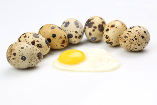 spotted eggs of partridges near the fried eggs on a white background.
