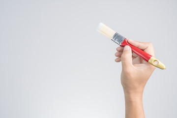 Hand holding new plastic paint brush with red handle