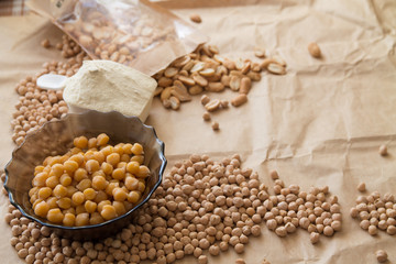 boiled and raw chickpea, peanuts and protein powder laying on a piece of craft paper