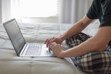 College student working on laptop on bed