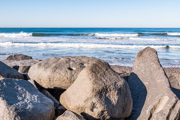 Large boulders on South Carlsbad State Beach in San Diego, California with waves in the background.