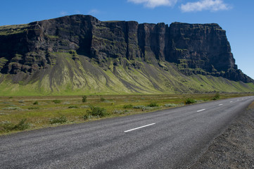 volcanic cliffs over empty road