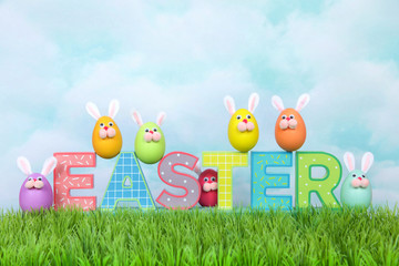Colorful decorated Easter Eggs with bunny faces and ears sitting on and around decorative letter blocks spelling EASTER. Fun holiday concept.