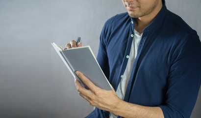 Man writing on notebook on grey background