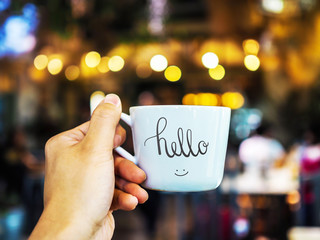 Hello text hand writing on cup with hand holding