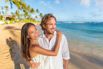 Happy couple in love on beach sunset vacation. Multiracial woman hugging husband people portrait on...