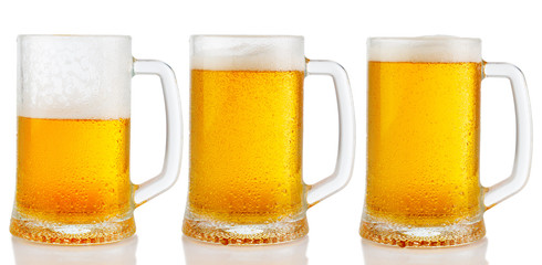Set of mugs of cold light beer with foam isolated on white background