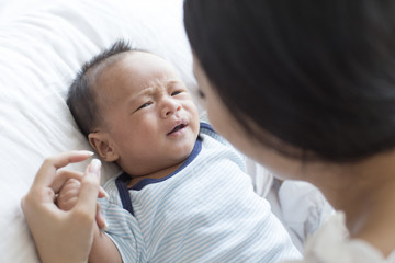 Fototapeta na wymiar Asian newborn baby crying on bed.