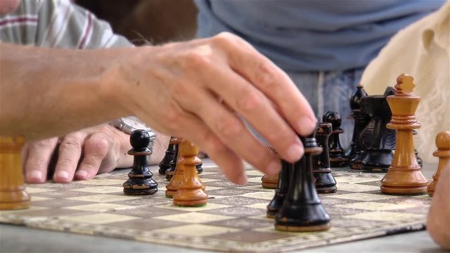 Two Senior Men playing Chess and others Watching at a Public Park in Buenos Aires, Argentina. Close Up.