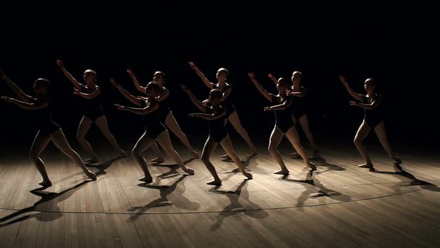 A choreographed dance of a group of graceful pretty young ballerinas practicing on stage in a classical ballet school. Children are taught ballet positions in choreography. Ballet. Scene.