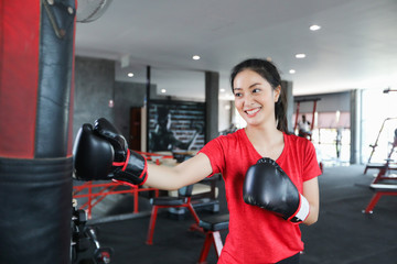 Beautiful women asian boxer happy and fun fitness boxing and Punching A Bag With wearing boxing...
