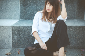 Young business woman sitting on floor. Casual business girl looking away.
