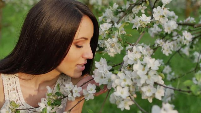 Girl smelling a blooming apple tree