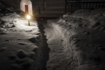 Cleaned path in the backyard at night with the light of a lantern.