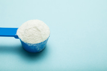 A blue spoonful of milk powder, empty space for text.