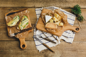 Healthy sandwiches with avocado, cheese and herbs on wooden board, top view.