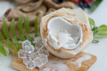 Coconut Milk Ice Cream and Young Coconut on a wooden plate with ice cubes and fruit as background