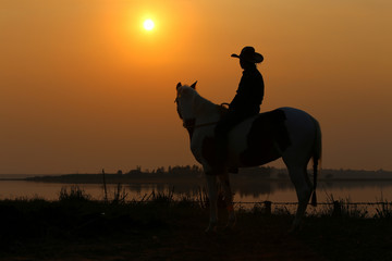 Alone cowboy silhouette on horseback at sunset America style