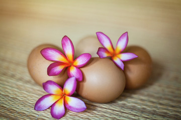 Fototapeta na wymiar Four natural brown eggs with flowers are lieing on the straw rug