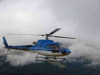 Blue helicopter flying in fog