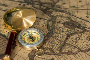 Retro compass with old map and magnifier