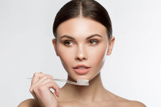 Portrait of confident young woman holding a toothbrush near her mouth. Isolated