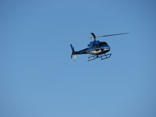 Blue helicopter flying on blue sky