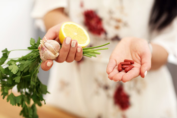 Young woman holding medicine and lemon garlic parsley