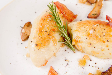 Traditional polish dish called kartacz - potato dumplings stuffed with meat and served with crispy bacon, caramelized onion and fried boletus